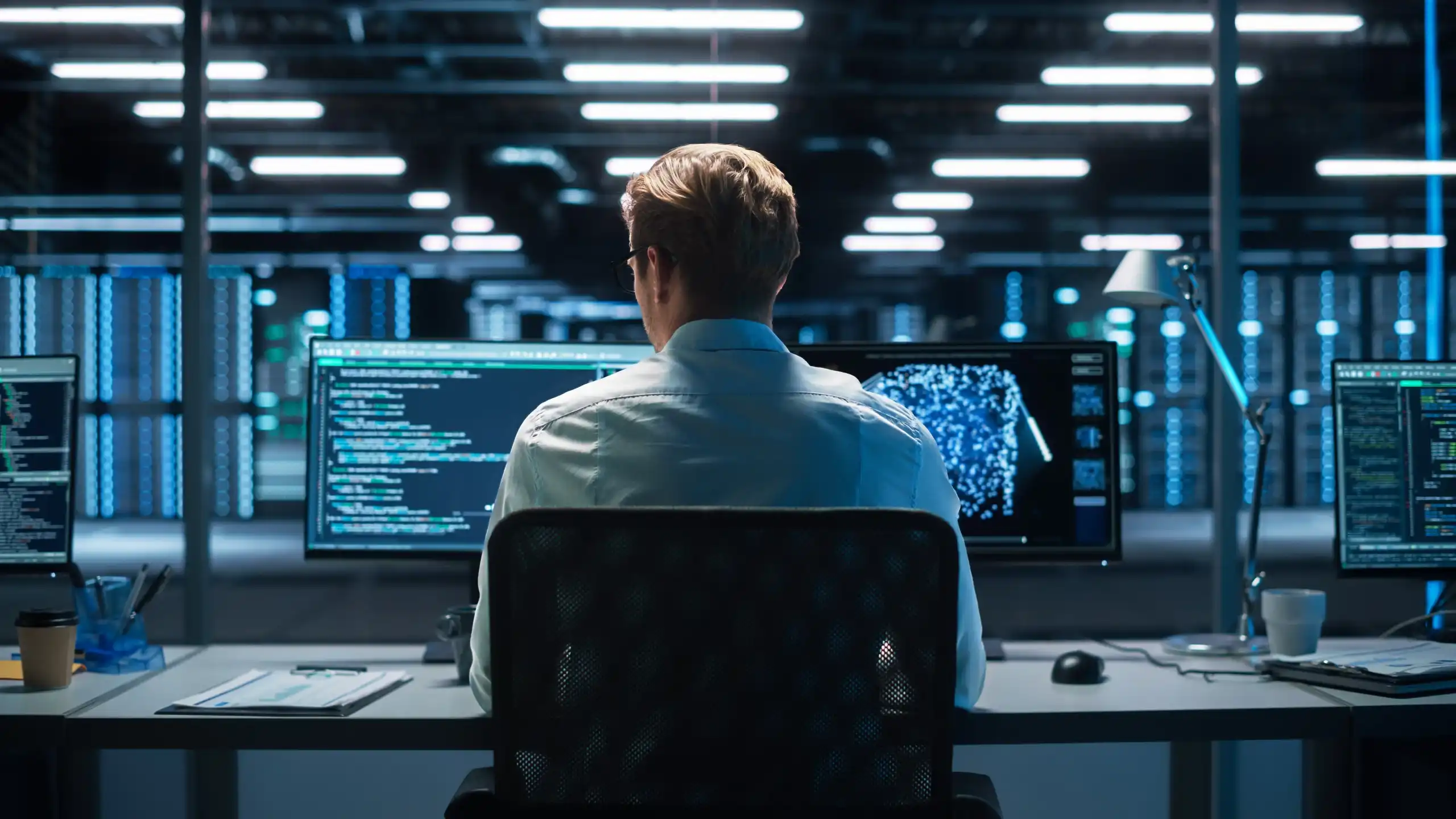 Personne assise devant un écran affichant du code informatique
