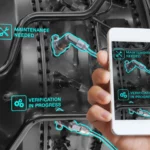 Une personne examine l'intérieur d'une machine nécessitant une maintenance en utilisant son téléphone portable qu'elle tient dans sa main.