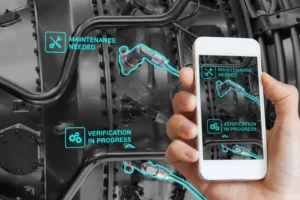 Une personne examine l'intérieur d'une machine nécessitant une maintenance en utilisant son téléphone portable qu'elle tient dans sa main.