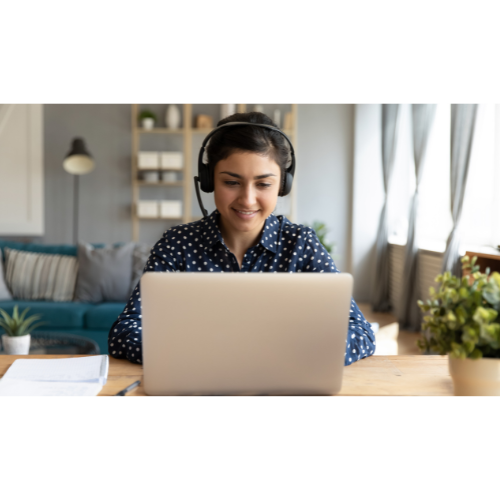 Femme portant un casque audio micro se tenant devant un ordinateur.