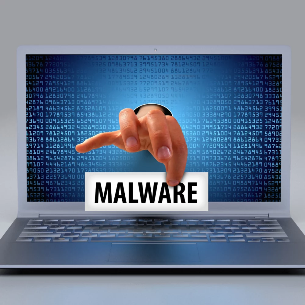 main sortant d'un pc avec une étiquette ou il y'a marqué "Malware"