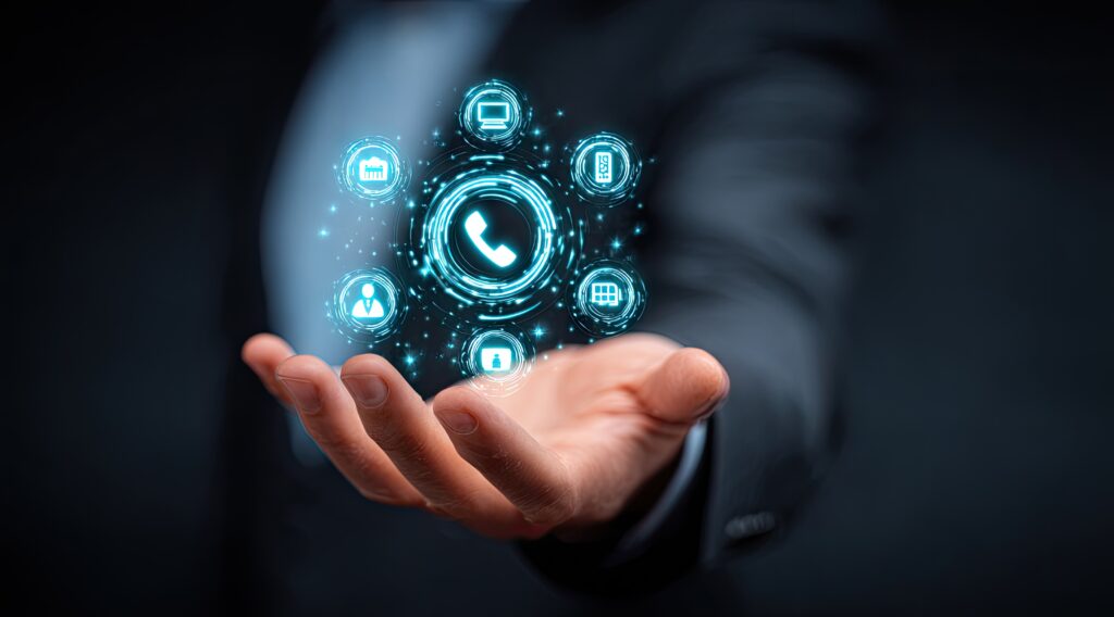 Main tenant une icône lumineuse représentant un téléphone numérique, entourée d'autres symboles de communication, représentant une technologie de communication intégrée.